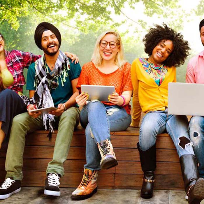 Foto de um grupo de estudantes ao ar livre, usando laptops.