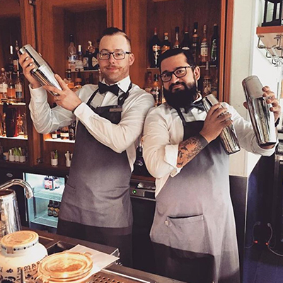 Two bartenders mixing drinks.