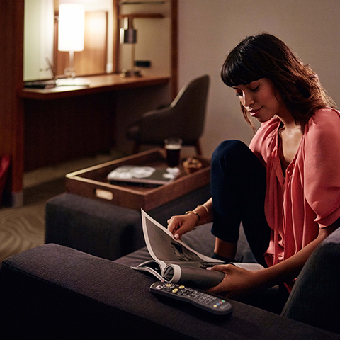 Una mujer moderna lee en la habitación de su hotel SpringHill Suites by Marriott.