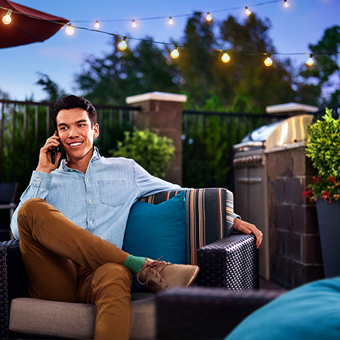 Un jeune professionnel ayant une conversation téléphonique dans le patio d’un hôtel Townplace Suites by Marriott.