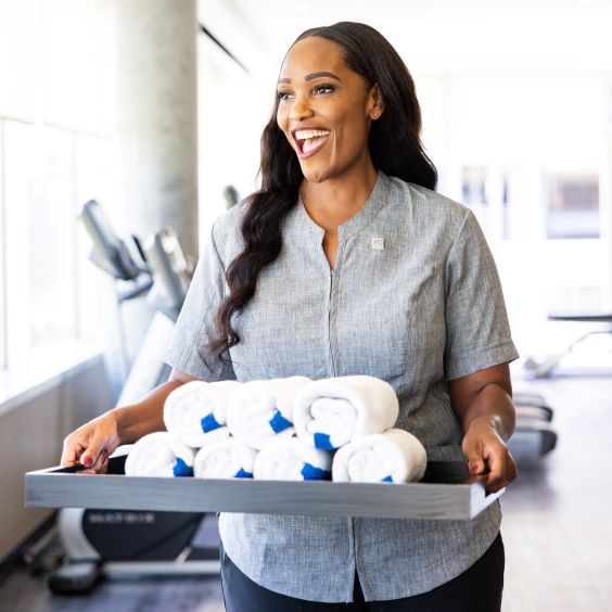 Smiling employee carrying a tray of towels