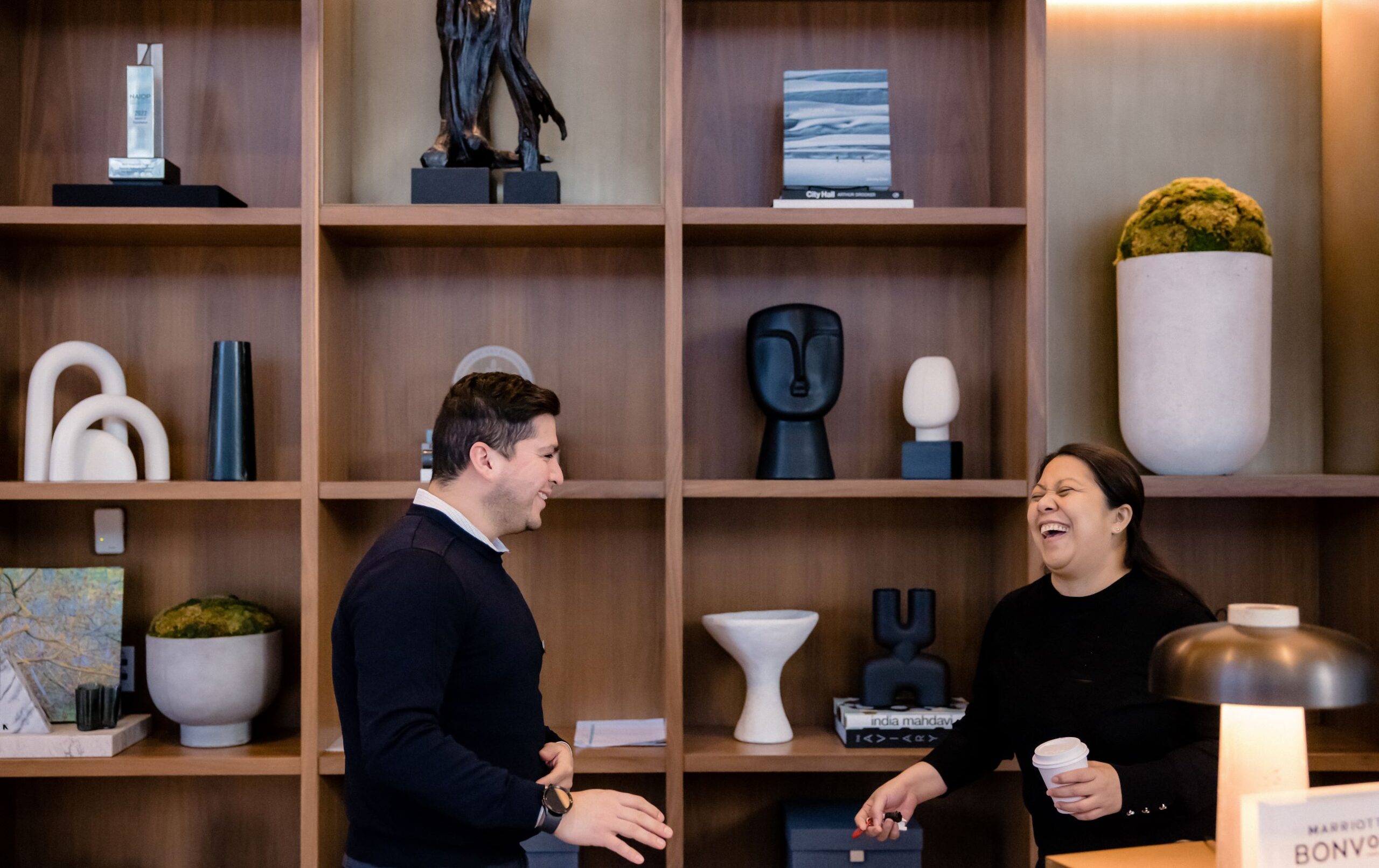 Two associates laughing together behind the front desk
